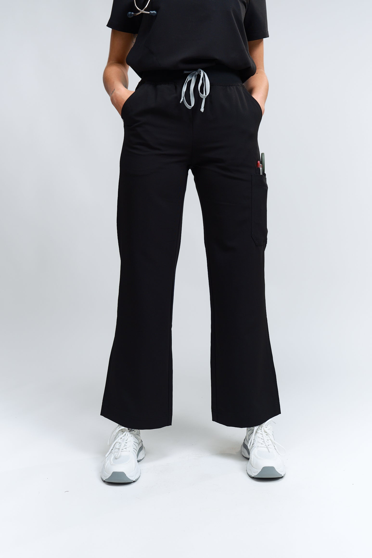 A person standing wearing high-waisted black wide leg scrub pants with an elastic waistband and antimicrobial fabric.